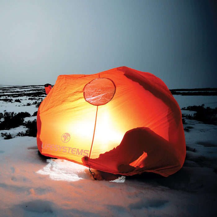 Lifesystems 4 man survival shelter being used in the snow and illuminated at night