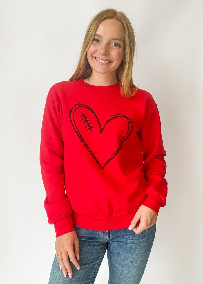 Person wearing a red sweatshirt with a black heart design on a plain background