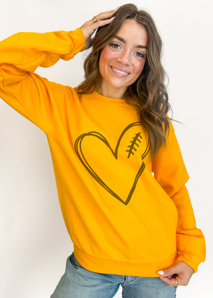Woman wearing a yellow sweatshirt with a heart design on a plain background