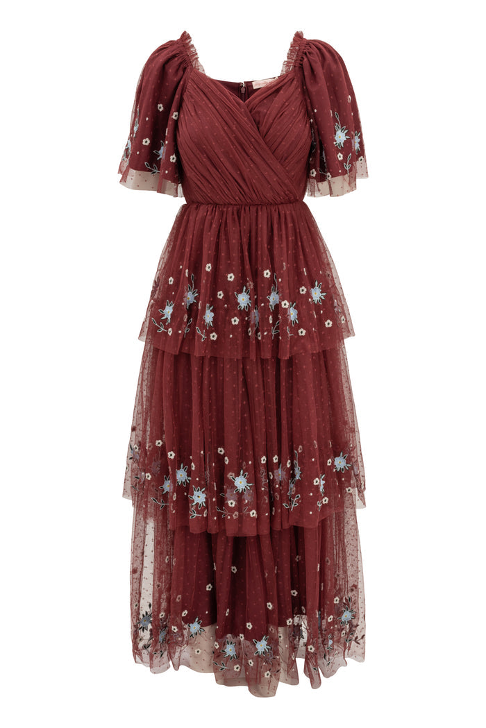 The Mabel Dress in Burgundy by Ivy City Co is a stunning maxi dress with layered tulle, short puff sleeves, a wrap-style bodice, blue and white floral embroidery, tiered silhouette, and delicate polka-dot details—perfect for a fall wedding.