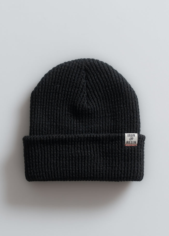 A black ribbed beanie with a folded brim and a small "Iron and Resin" label on a light gray background.