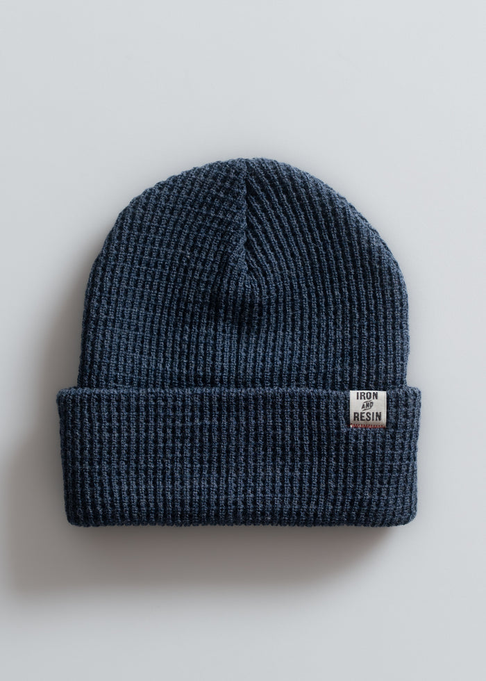 A blue knit beanie with a folded brim and an "Iron and Resin" label, displayed on a plain white background.