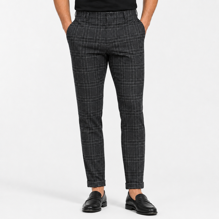 Men's black plaid pants close-up showing the waistband, front button, belt loops, pockets, checked pattern, seams, and cuffs.