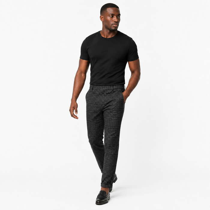 Men's black plaid pants shown in a walking pose, one hand in a pocket, highlighting loose movement and easy everyday styling.