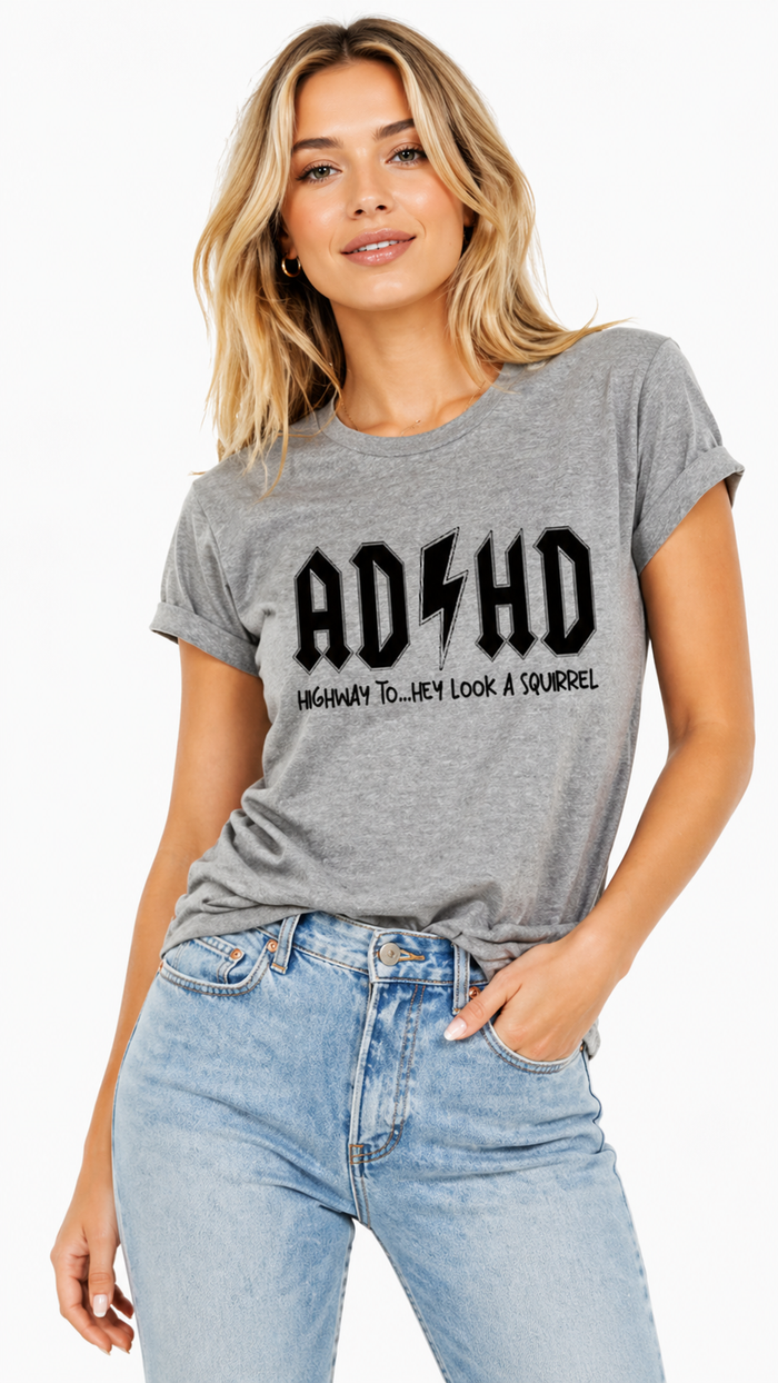 Woman wearing a gray t-shirt with 'ADHD Highway to Nowhere' text, standing against a white background.