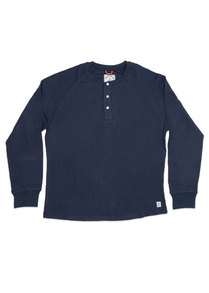 Navy blue long-sleeve henley shirt with four buttons and a small logo tag at the hem, laid flat on a white background.