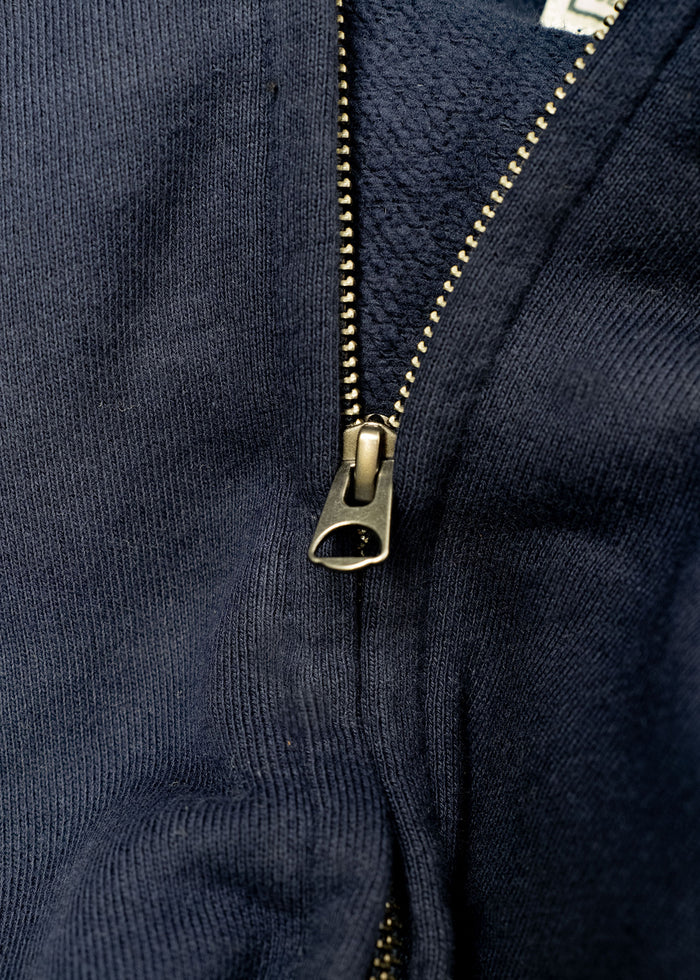Close-up of a navy blue jacket with a partially open metal zipper, revealing a textured inner lining.