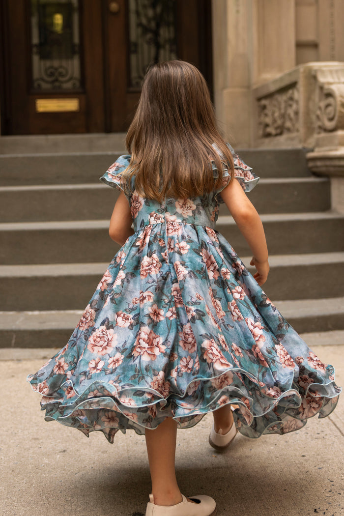 A young girl in the Ivy City Co Mini Lisette Dress in Rose Dusk walks up stone steps toward a building, her back to the camera—the perfect scene for a fall wedding.
