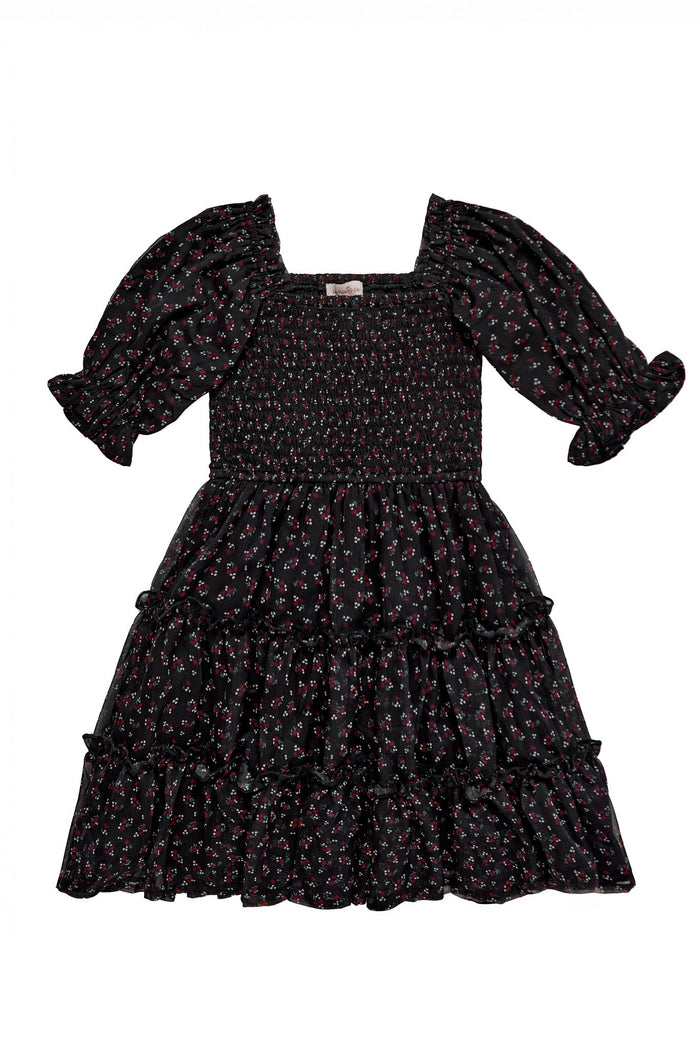 The Mini Madeline Dress in Black Ditsy Floral by Ivy City Co features puff sleeves, a smocked bodice, and a square neckline with a tiered ruffle skirt. This charming mini dress is crafted from black fabric adorned with a subtle red and white ditsy floral print for an effortlessly feminine look.