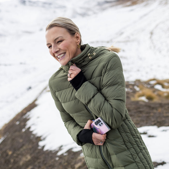 Woman wearing Moke - Sydney Cloud Touch 90/10 Down Coat (SYDNEY) in the colour Olive Green on a hill with snow in the background.