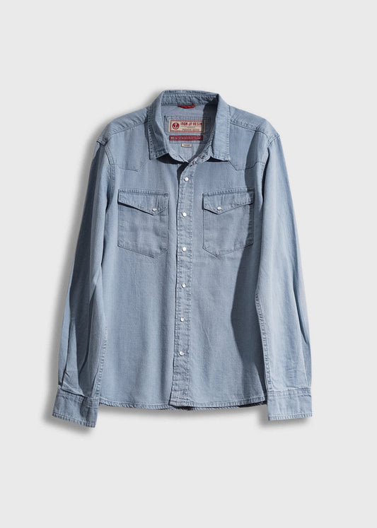 Light blue denim shirt with long sleeves and buttoned chest pockets, displayed on a white background.