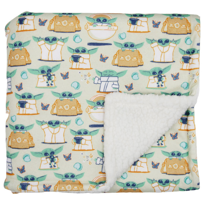 The Sassy Woof Pet Blanket - STAR WARS™ The Child™ features a soft, colorful pattern of cartoon Baby Yoda, spaceships, and stars with a white sherpa lining—officially licensed by Lucasfilm.