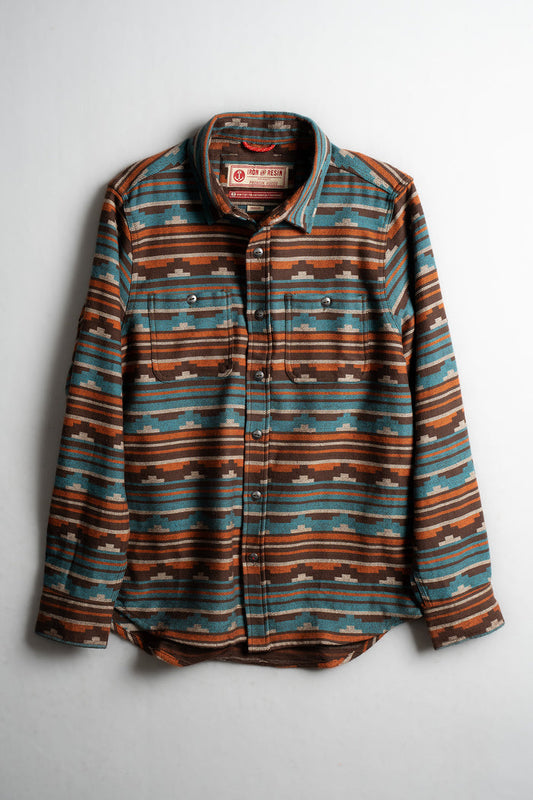 Striped flannel shirt with brown, blue, and orange patterns, featuring buttoned front and collar, displayed on a white background.
