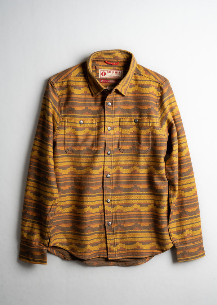 Brown and yellow striped flannel shirt with button closure and two chest pockets, displayed on a light background.