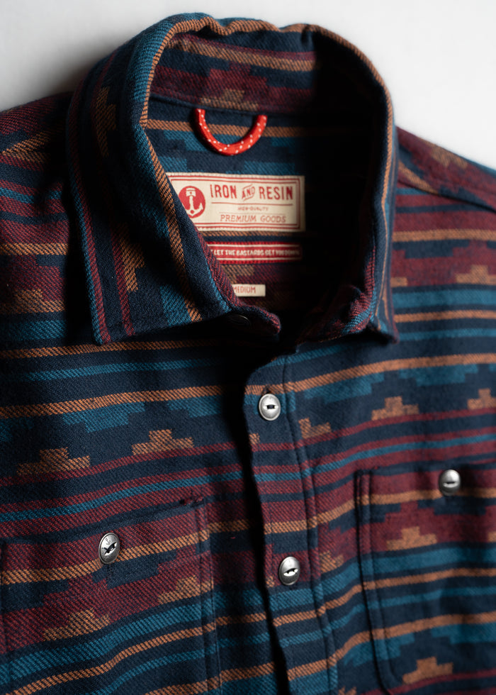 Iron & Resin shirt with geometric pattern in blue, red, and brown, featuring metal buttons and a visible brand label inside the collar.