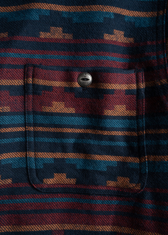 Close-up of a fabric with geometric patterns in blue, red, and orange. A buttoned pocket is visible in the center.