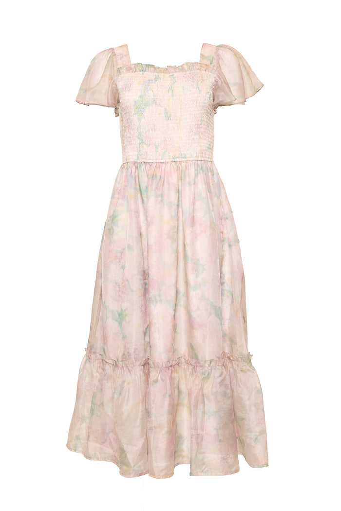 The Ivy City Co Rhiannon Dress in Painted Bloom features a pastel watercolor floral print, flutter sleeves, smocked bodice, ruffled hem, and airy fabric—an ankle-length maternity-friendly style in pale pink and green.