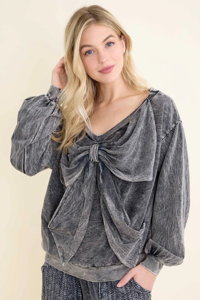 Mineral washed off-the-shoulder top with a V neckline, long sleeves, and an oversized front ribbon bow detail.