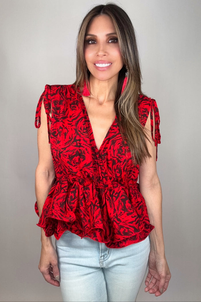Sleeveless red and black abstract rosette print peplum blouse with a deep V neckline, tie shoulders, and layered ruffle hem.