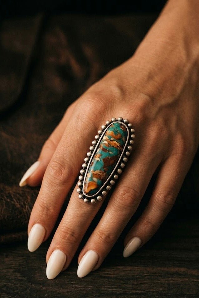 Western-style turquoise statement ring with elongated stone and silver bead trim on hand