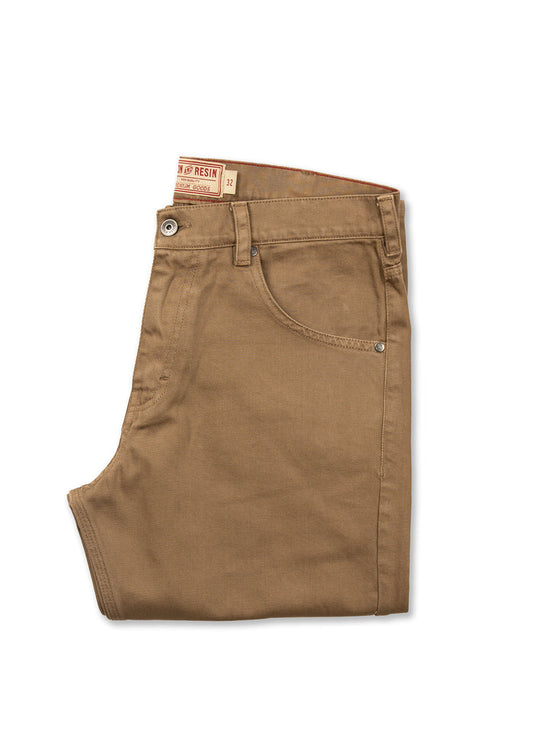 Folded brown pants with a visible label, showcasing a classic design and button detail, isolated on a white background.