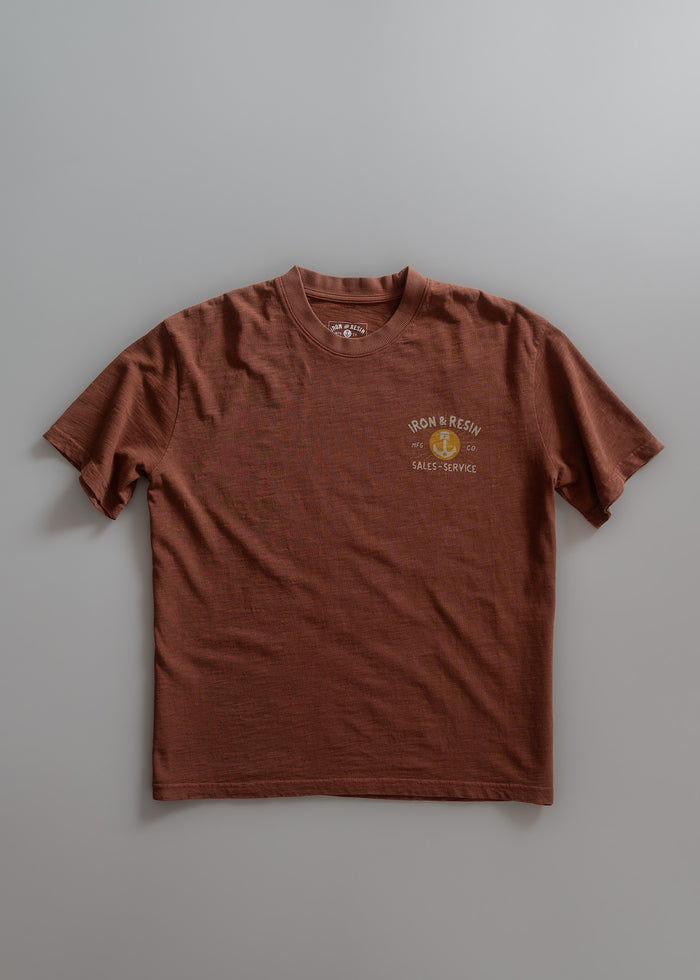 Brown T-shirt with "Iron & Resin Sales Service" logo on chest, displayed on a plain gray background.