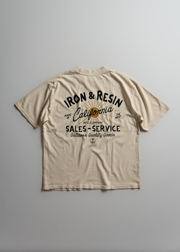 Beige T-shirt with "Iron & Resin, California" text, featuring outdoor quality goods design, laid flat on a gray background.
