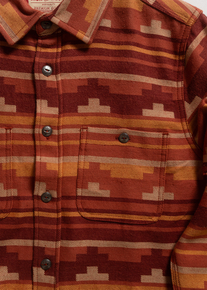 Rust-colored patterned shirt with geometric design, buttoned front, and two chest pockets, showcasing a warm, earthy style.