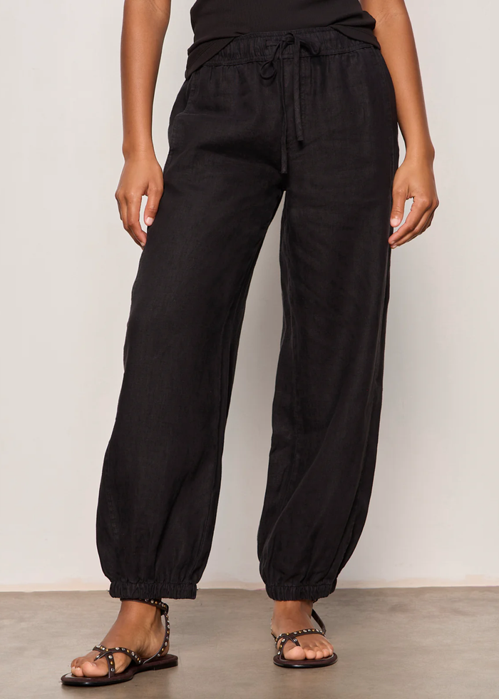 Woman wearing black linen joggers with a black tank top and sandals