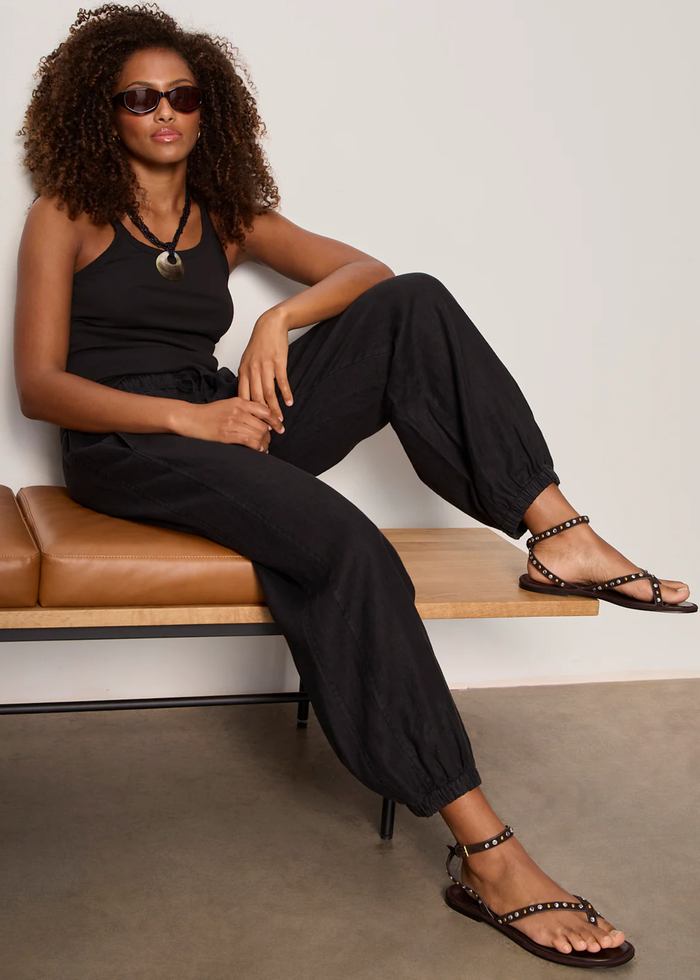 Woman wearing black linen joggers with a black tank top and sandals