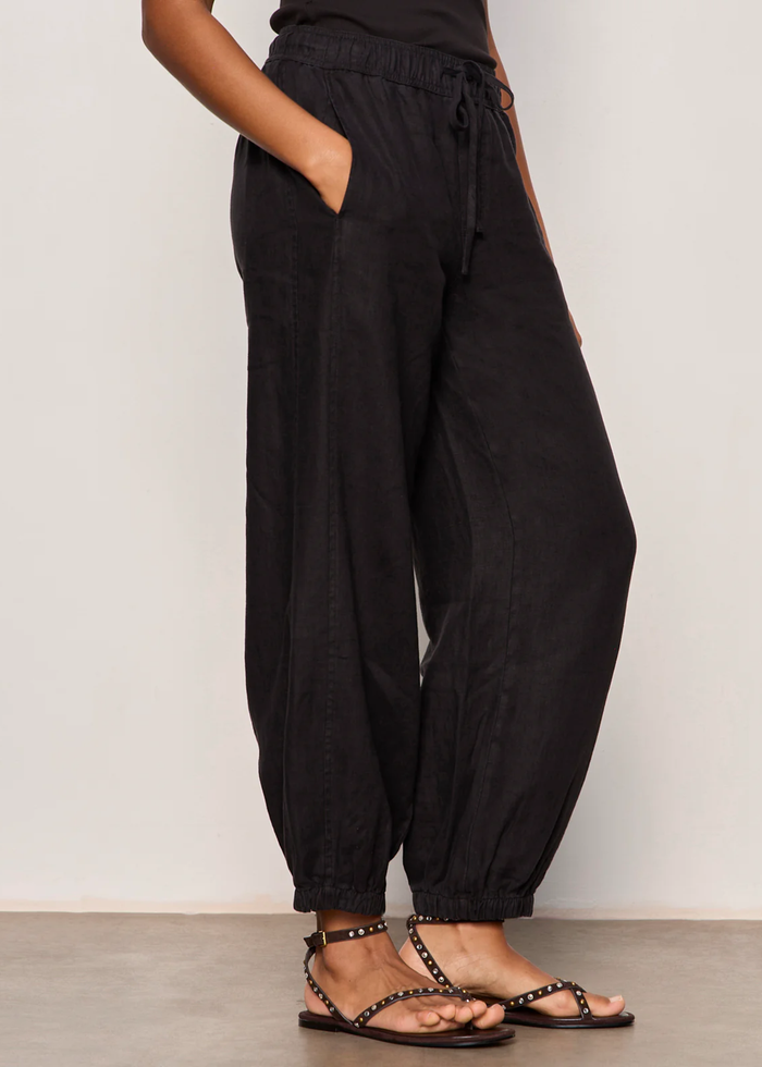 Woman wearing black linen joggers with a black tank top and sandals
