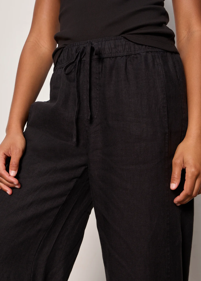 Woman wearing black linen joggers with a black tank top and sandals