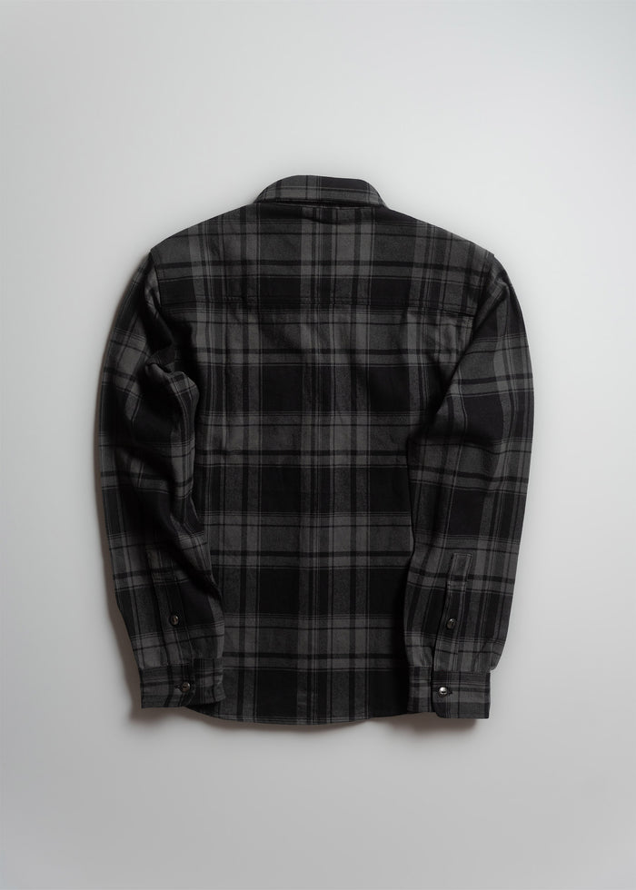 A black and gray plaid flannel shirt is laid flat, showcasing its back and long sleeves, against a plain white background.