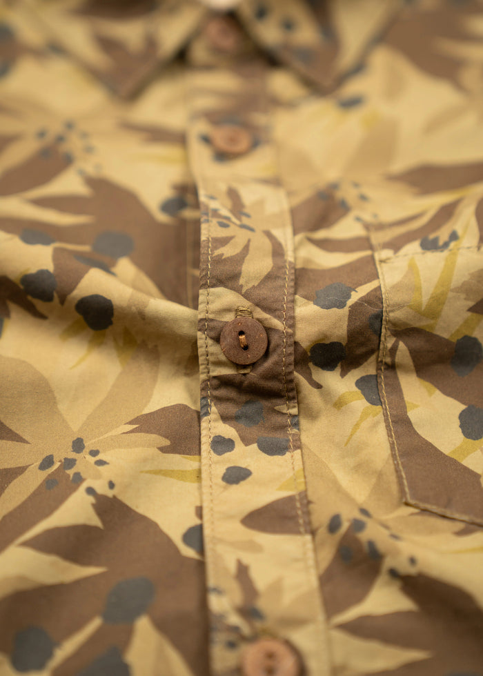 Close-up of a beige and brown floral patterned shirt with wooden buttons, highlighting the fabric texture and button details.