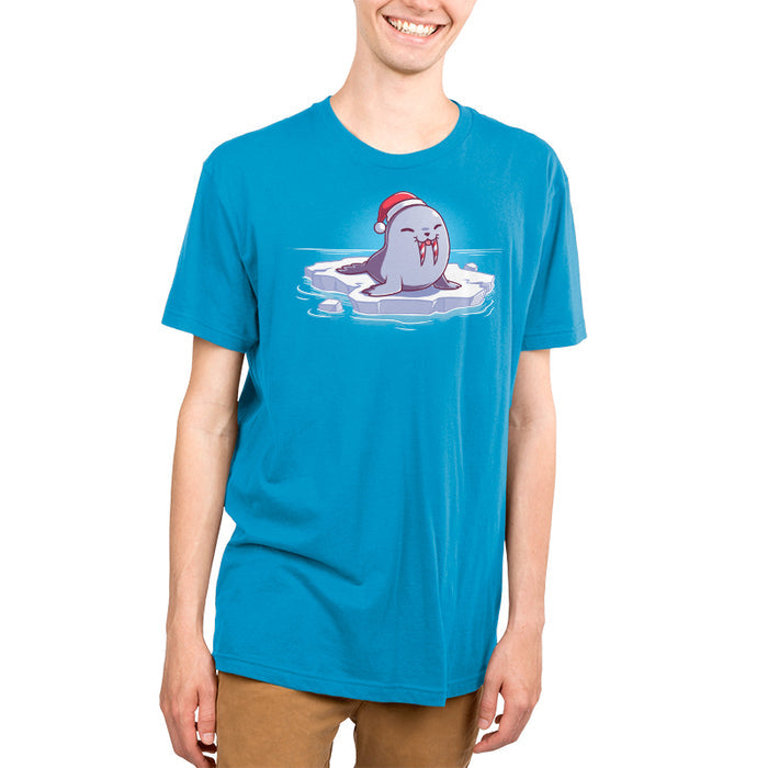 Premium Cotton T-shirt_TeeTurtle cobalt blue Sweet Tooth apparel featuring an illustration of a happy walrus sticking out it's tongue, wearing a Santa hat, and sitting on a floating ice. It's tusks are striped with red and white like candy canes.