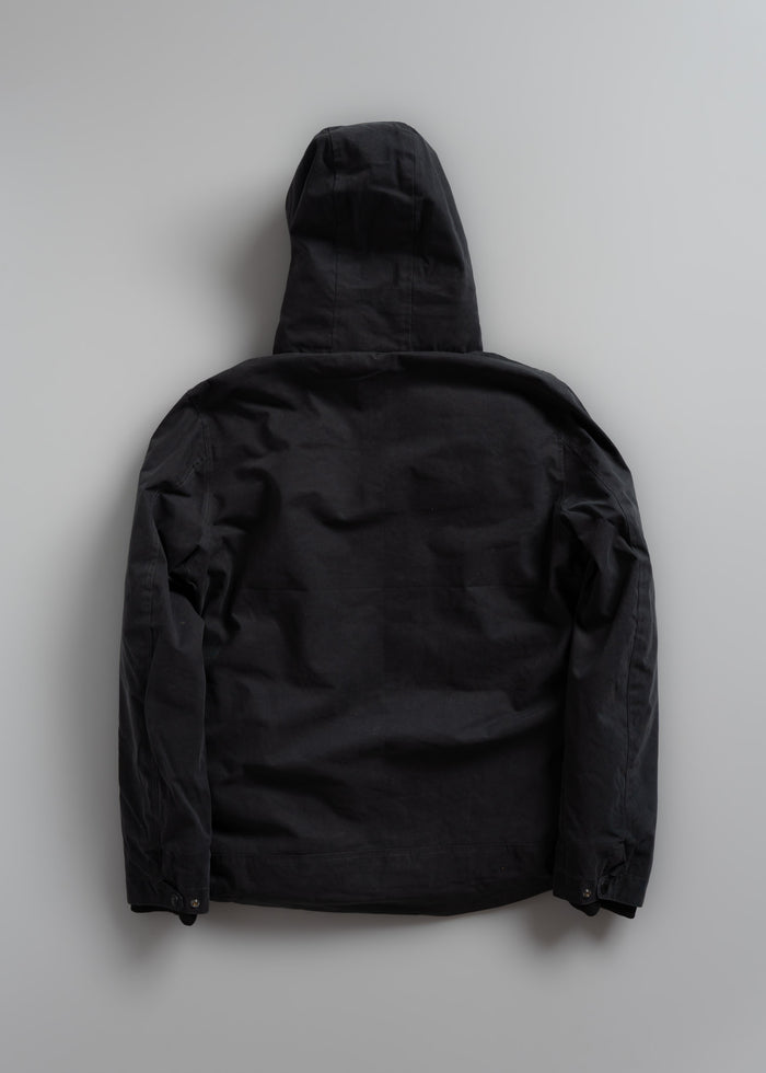 Black hooded jacket laid flat on a light gray background, showing the back view with long sleeves and a relaxed fit.
