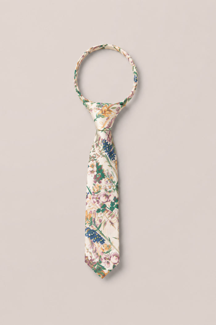 The Ivy City Co "Ties in Autumn Bouquet" is showcased with a neat knot, laid flat against a plain light background. This tie displays an array of colorful flowers and leaves in pink, green, and blue tones—making it the perfect cheerful accessory for family photos.