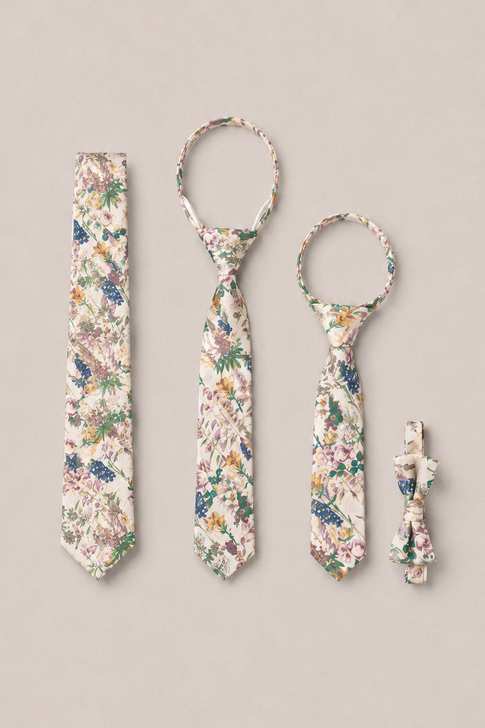 Four accessories from Ivy City Co’s Ties in Autumn Bouquet collection—a necktie for adults, a child’s tie, a bowtie, and a dog bowtie—are displayed on a simple background. Each piece features matching pastel and green botanical prints, making them perfect as wedding ties or for coordinating family photo tie sets.