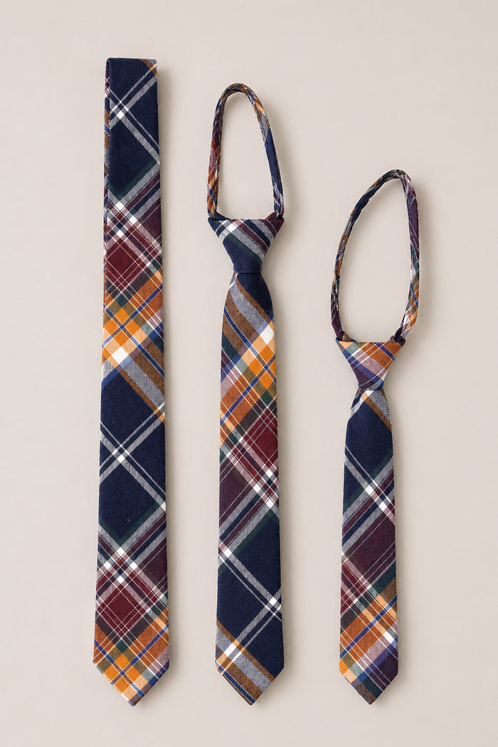 Three Ties in Midnight Plaid by Ivy City Co—available in adult, youth, and child sizes—are displayed side by side on a neutral background. Each tie is crafted from soft cotton and showcases a vibrant pattern of navy, orange, white, and burgundy stripes, making these ties the perfect wedding accessory for every family member.