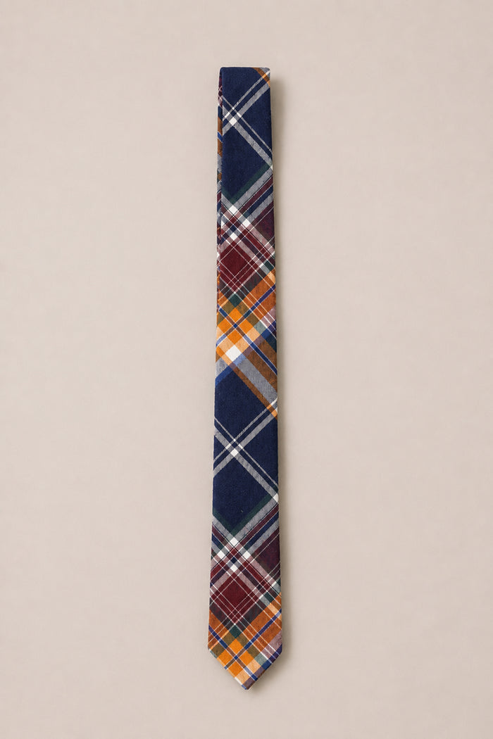 The Ivy City Co Ties in Midnight Plaid feature a narrow cotton design with a sophisticated diagonal plaid pattern in navy blue, orange, burgundy, white, and gray, set against a light beige background—making it the perfect wedding accessory.