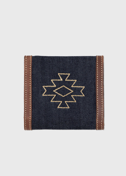 Denim wallet with brown leather trim, featuring a geometric embroidered pattern on the front, set against a plain background.