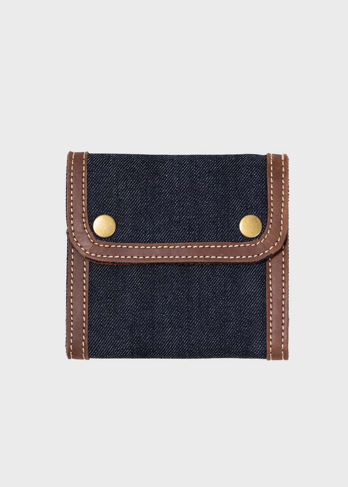 Denim wallet with brown leather trim and brass snap buttons, showcasing a stylish and compact design on a plain background.
