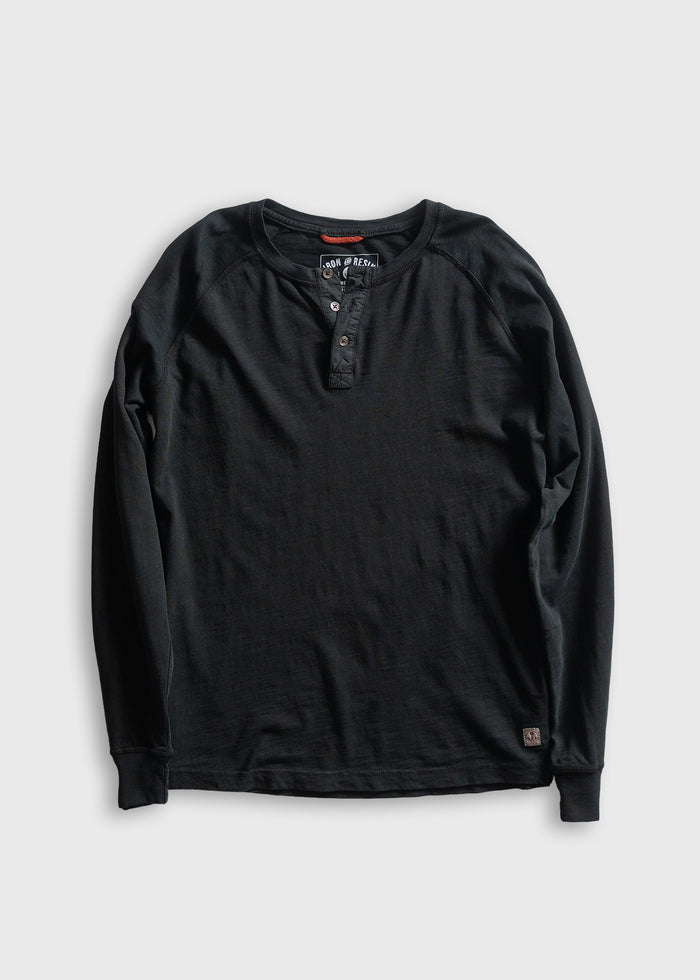 Black long-sleeve henley shirt with buttoned placket, displayed on a gray background. Simple, casual design for everyday wear.