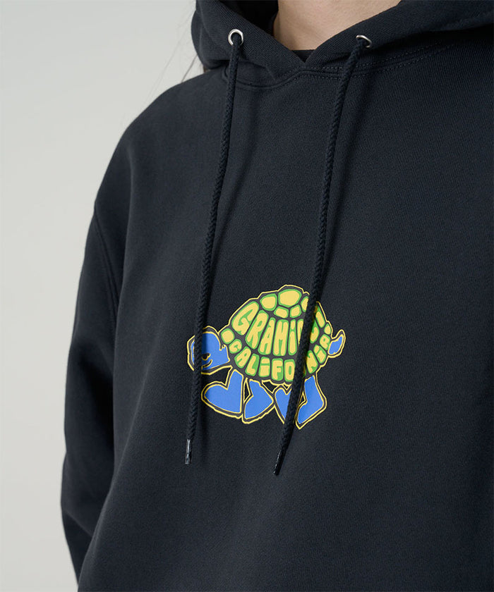 Model wearing a Gramicci vintage black Turtle Hooded Sweatshirt with turtle graphic against a light tone background.