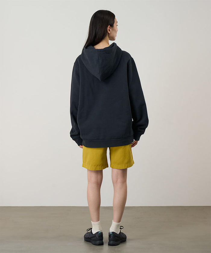 Back view of a model wearing a vintage black Gramicci Turtle Hooded Sweatshirt and yellow shorts on a light tone background.
