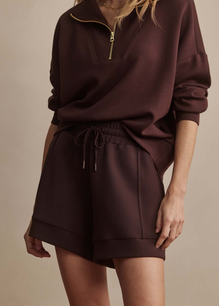 Woman wearing brown drawstring shorts with a matching quarter zip sweatshirt