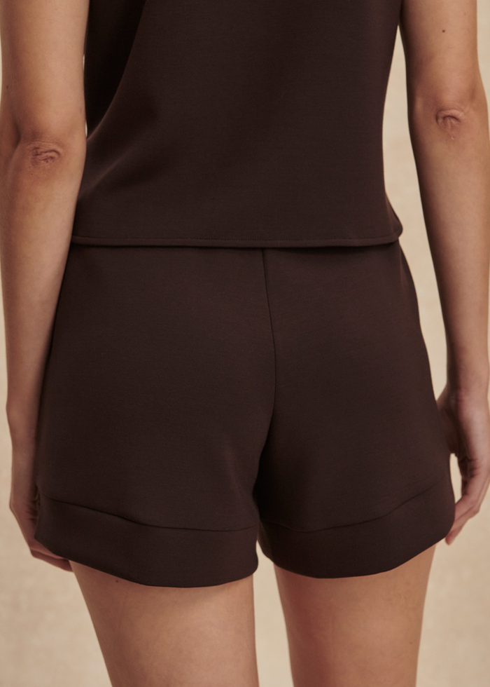 Woman turned around wearing brown drawstring shorts with a matching button down tank top
