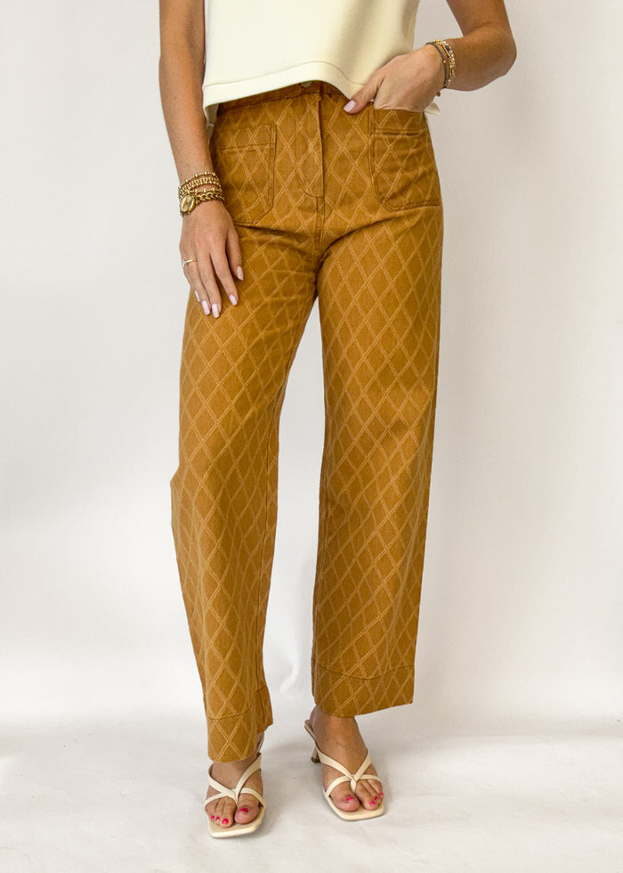 Person wearing mustard yellow patterned pants on a white background