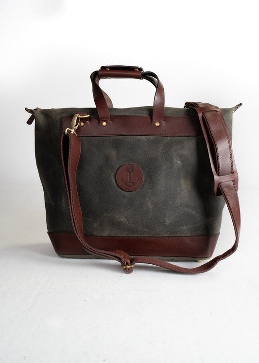 A stylish canvas tote bag with brown leather accents and an anchor logo, featuring a shoulder strap and sturdy handles.