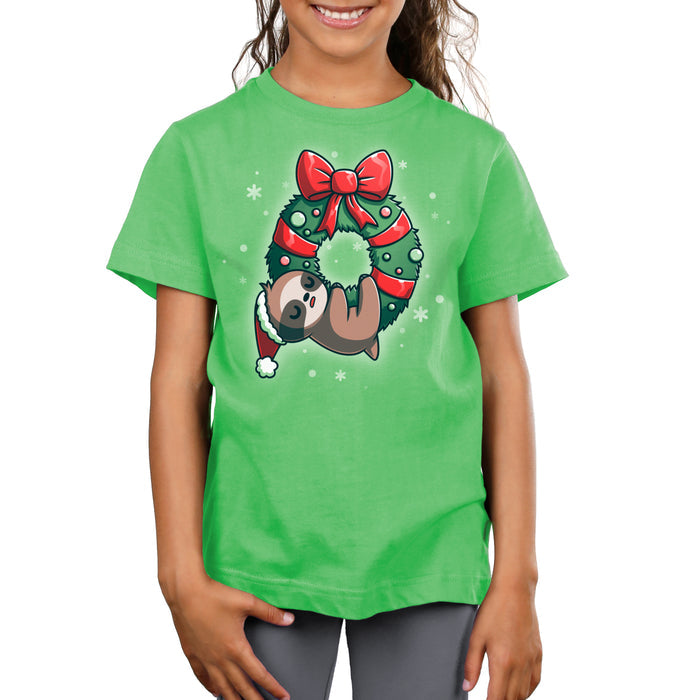 Premium Cotton T-shirt_TeeTurtle We Wish You a Lazy Christmas apple t-shirt featuring a cartoon sloth in a Santa hat, snoozing while hanging from a festive wreath adorned with red ribbons and ornaments.
